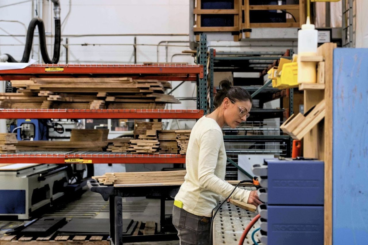 Women in yellow shirt standing at a work table in a workshop