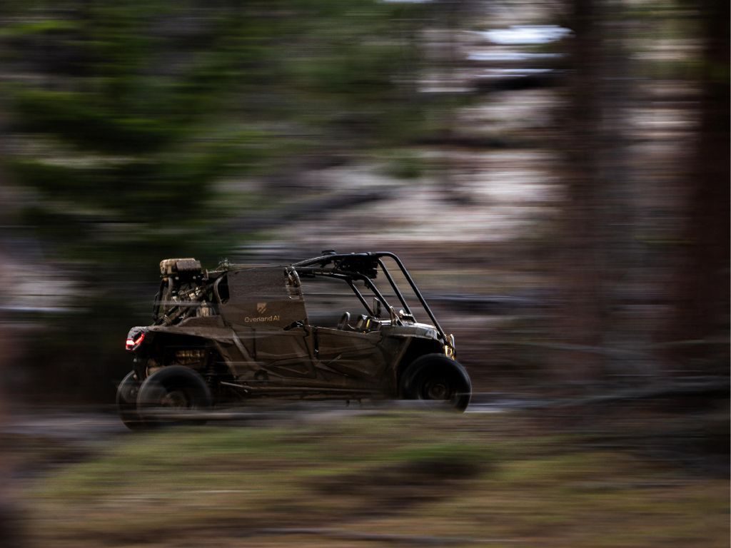 Autonomous military vehicle moving through trees in a dense forest