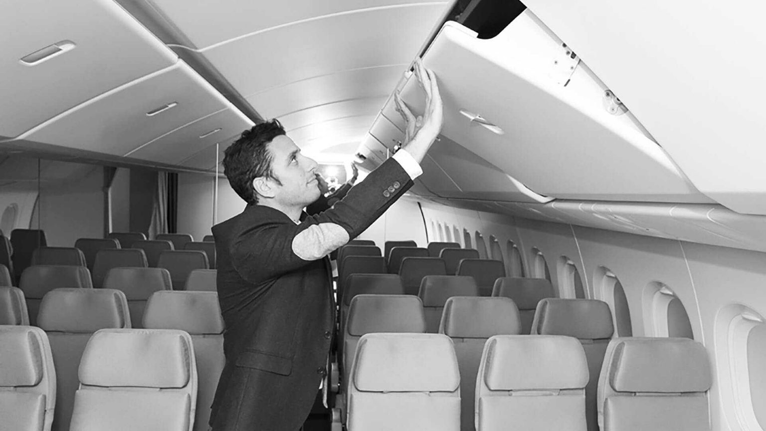 Man in suite jacket looking at airplane stowage bin