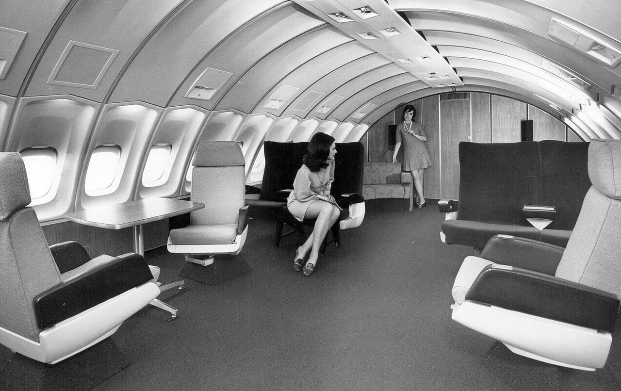 Two women posing in Boeing 747 mock up with large seats