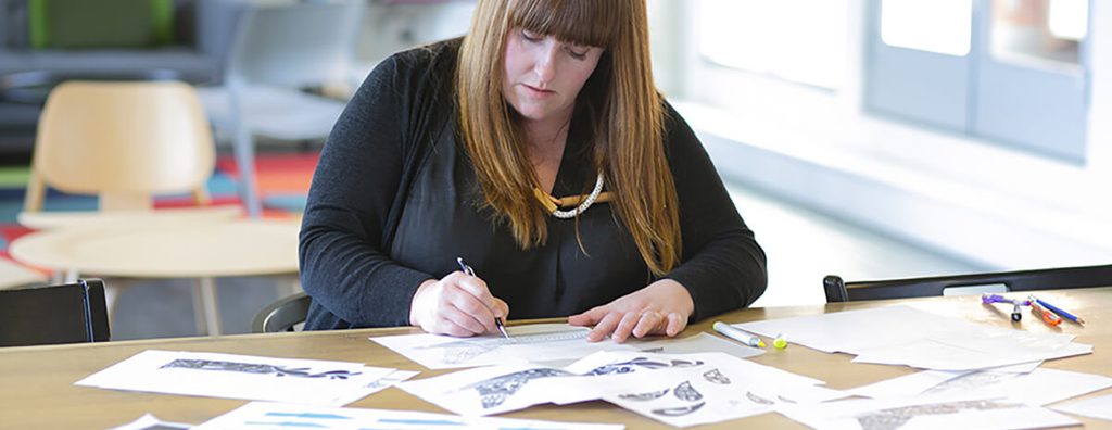 Women sitting at table sketching in modern office