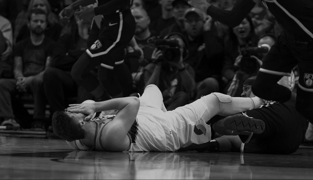 Professional basketball player laying on basketball count with an injury