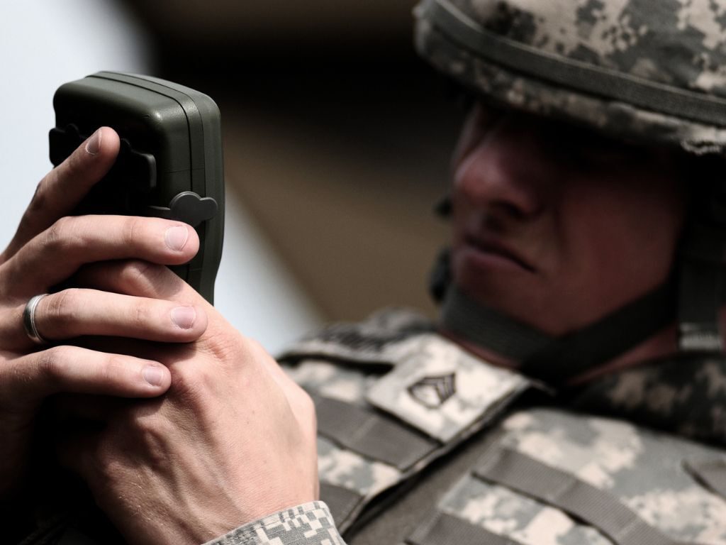 Man in camo looking at information on a black handheld device