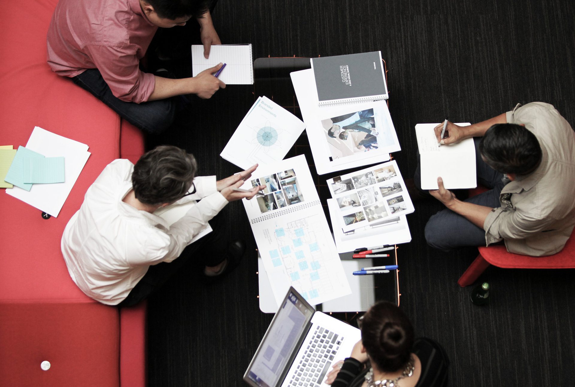 Creative team seating on red sofas looking at documents