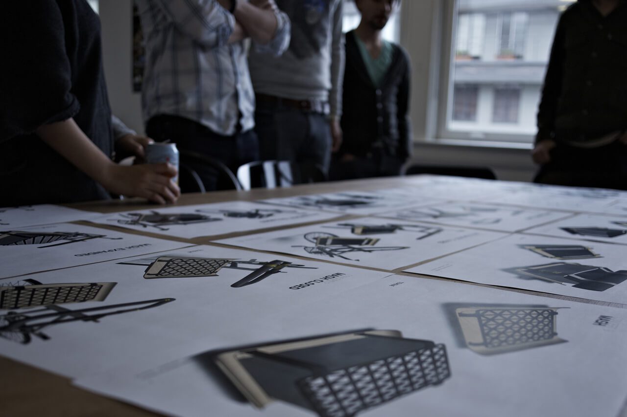 Sketches of Denny bike concepts laid out on table with a team reviewing them