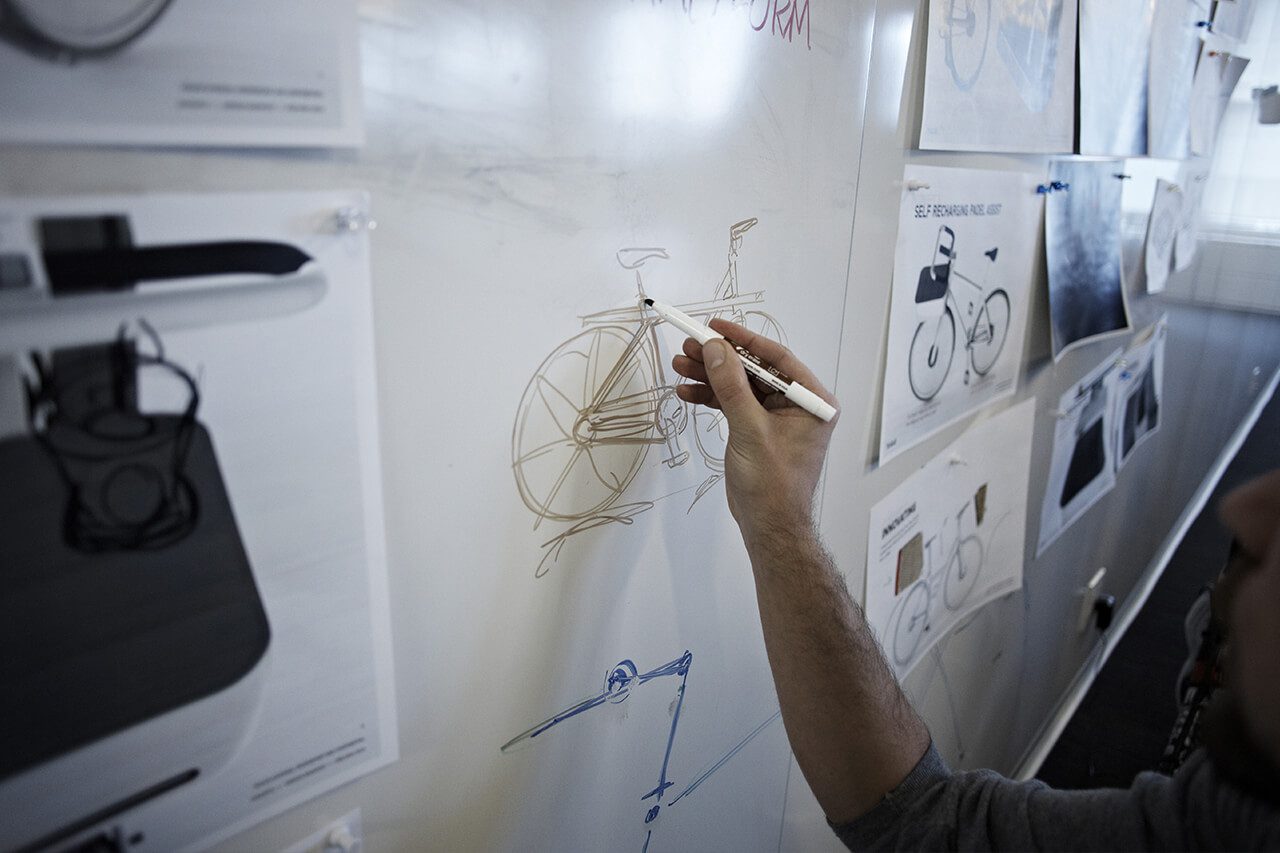 Man sketching ideas for conceptual bike on whiteboard