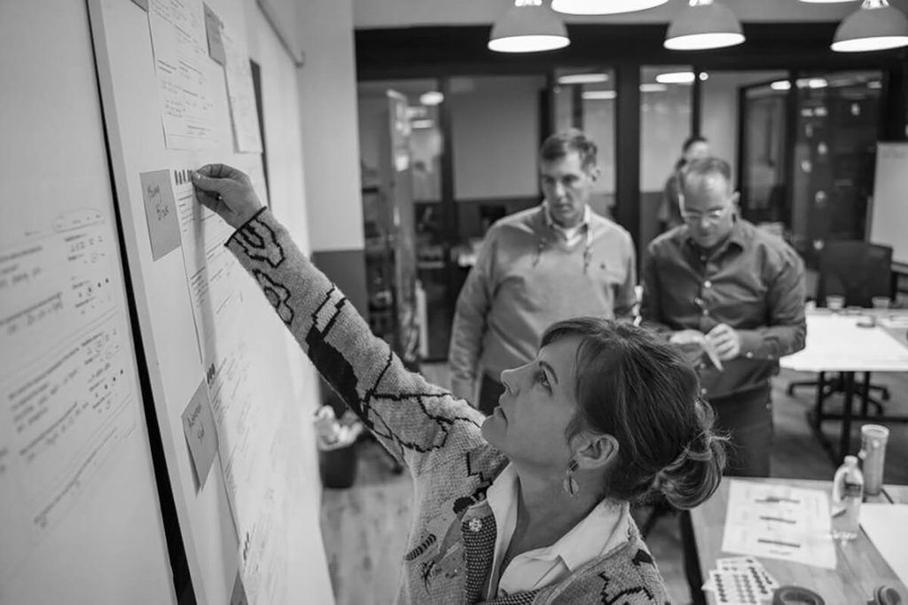 Women adding post it note to a white board