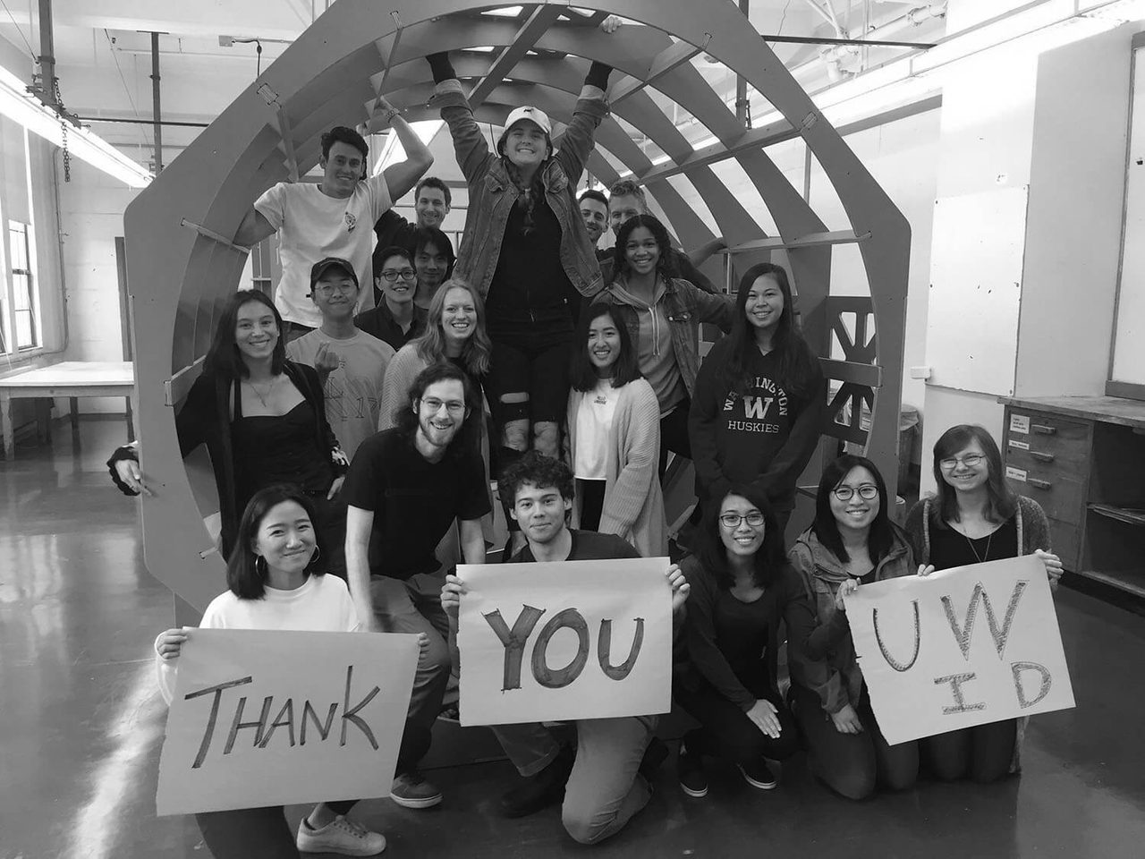 Students standing inside full scale mock up of spacecraft holding thank you signs