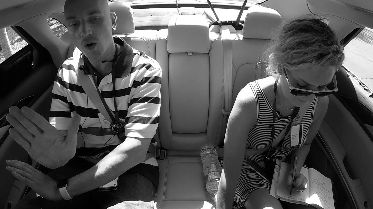 Man and woman sitting in backseat of a car with notebook conducting user research