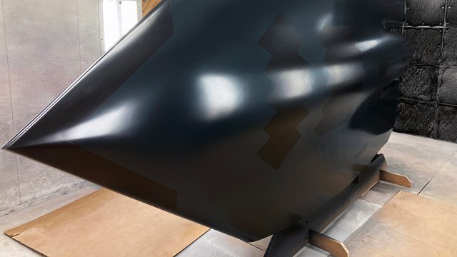 Freshly painted black VTOL fighter jet drying in large paint booth