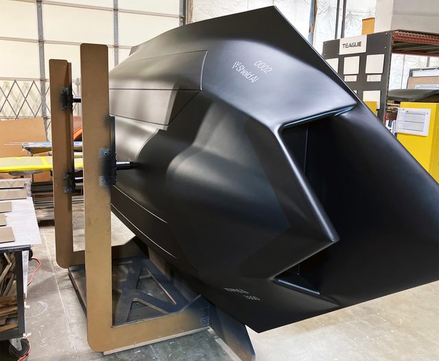 VTOL fight jet model laying on side in drying rack after being painted matte black