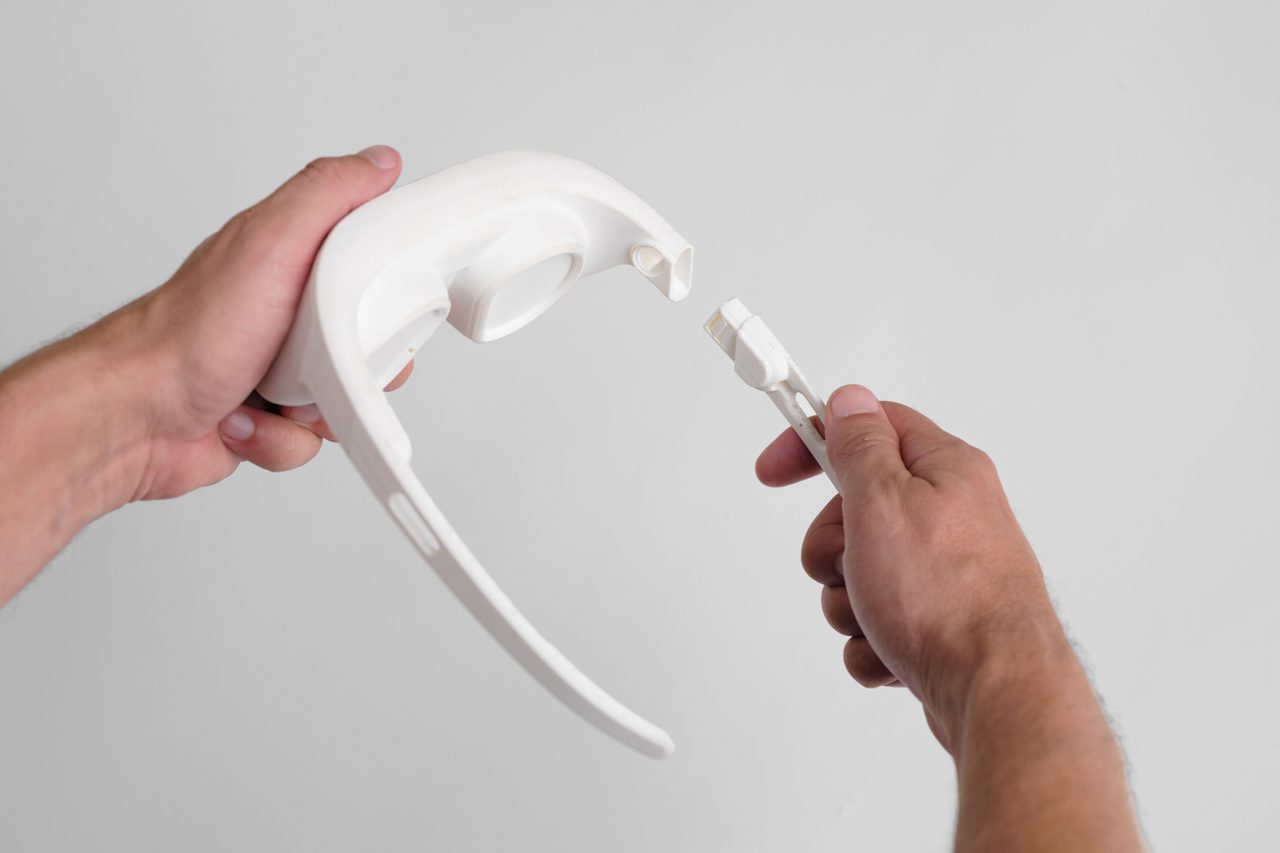 two hands taking white 3D printed VR headset apart