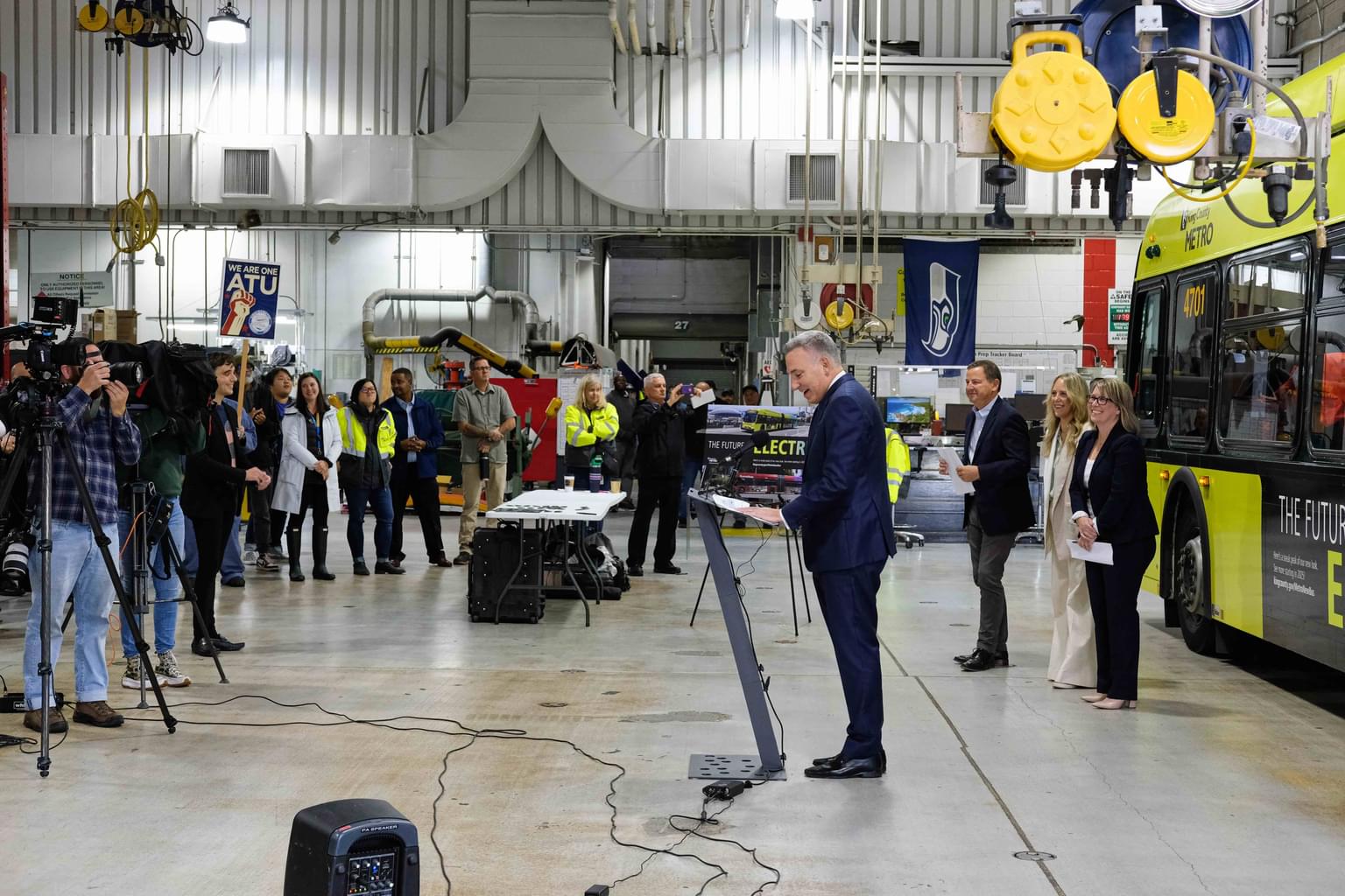 Dow Constantine speaks to the press about Teague's new designs for the King County Metro bus, which is behind him.