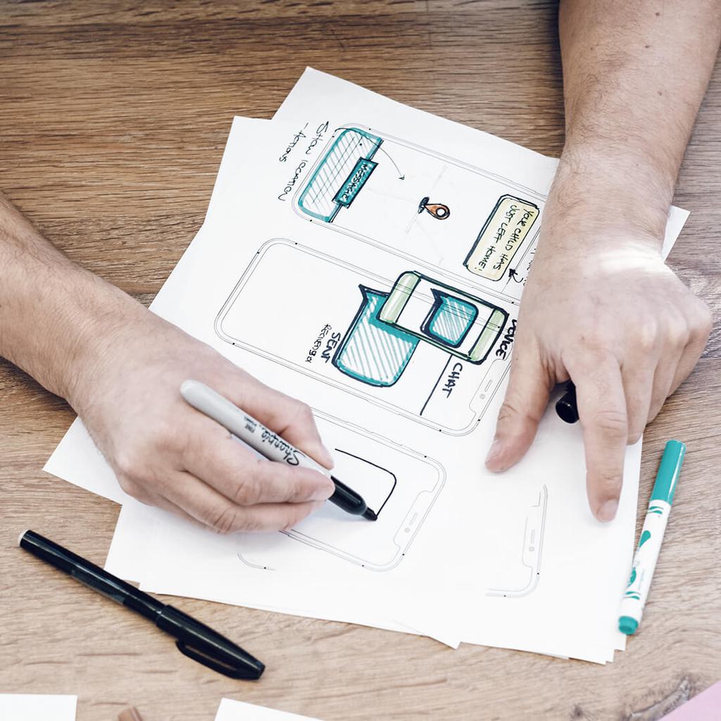 Hands sketching phone under interface on wood table