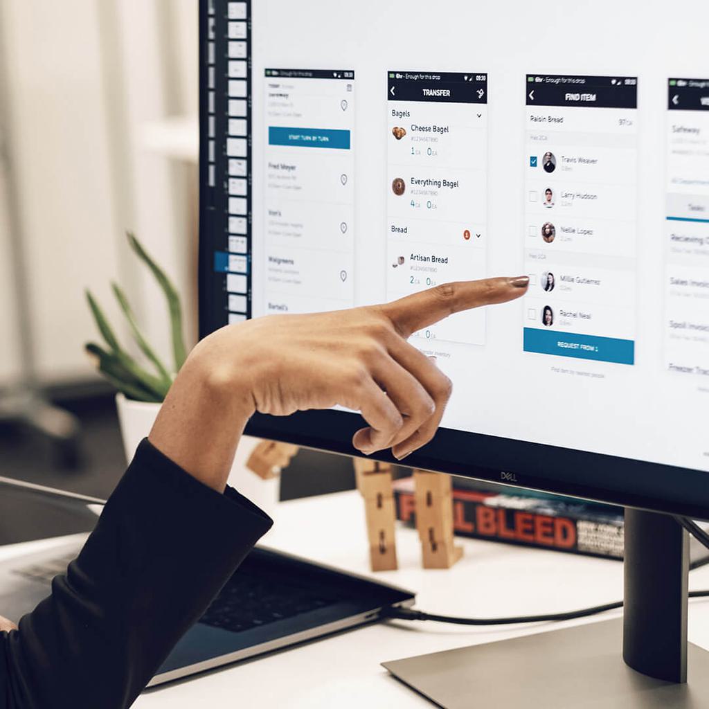 Finger pointing at computer screen with user interface mockups