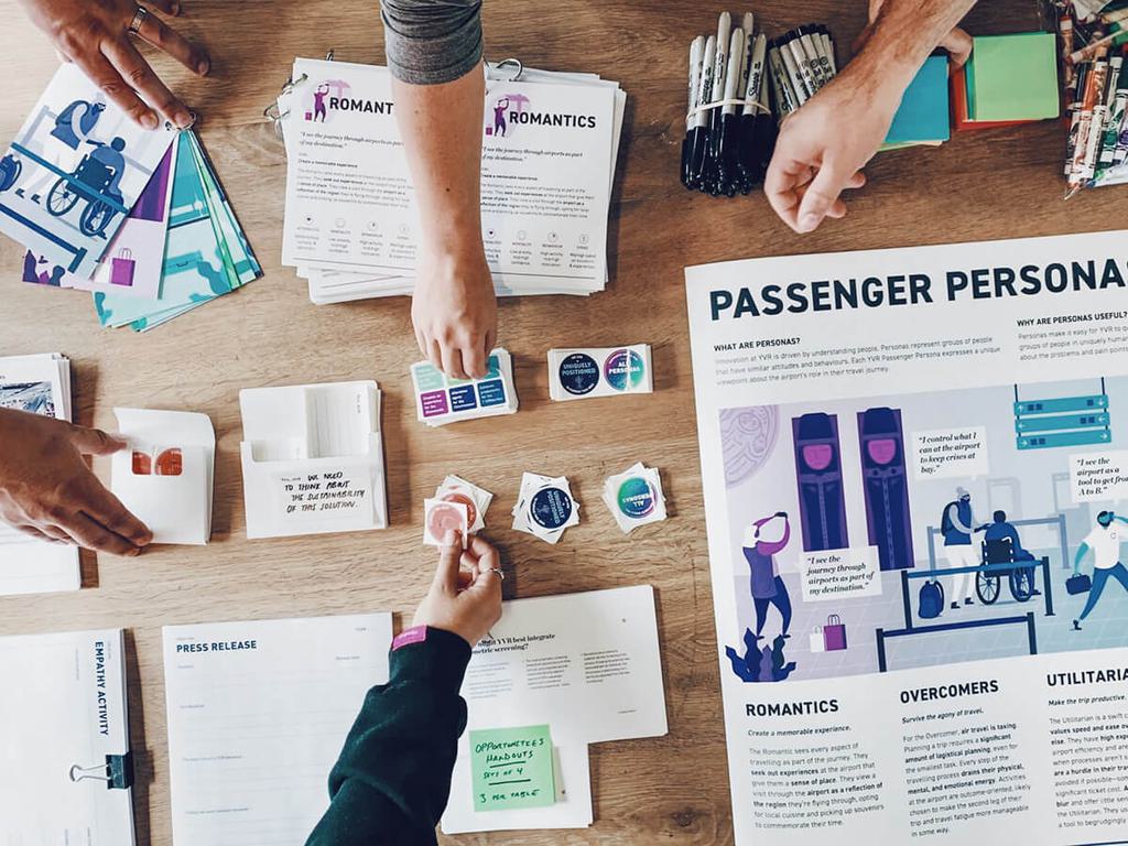 Hands picking up worksheets and stickers for a design workshop