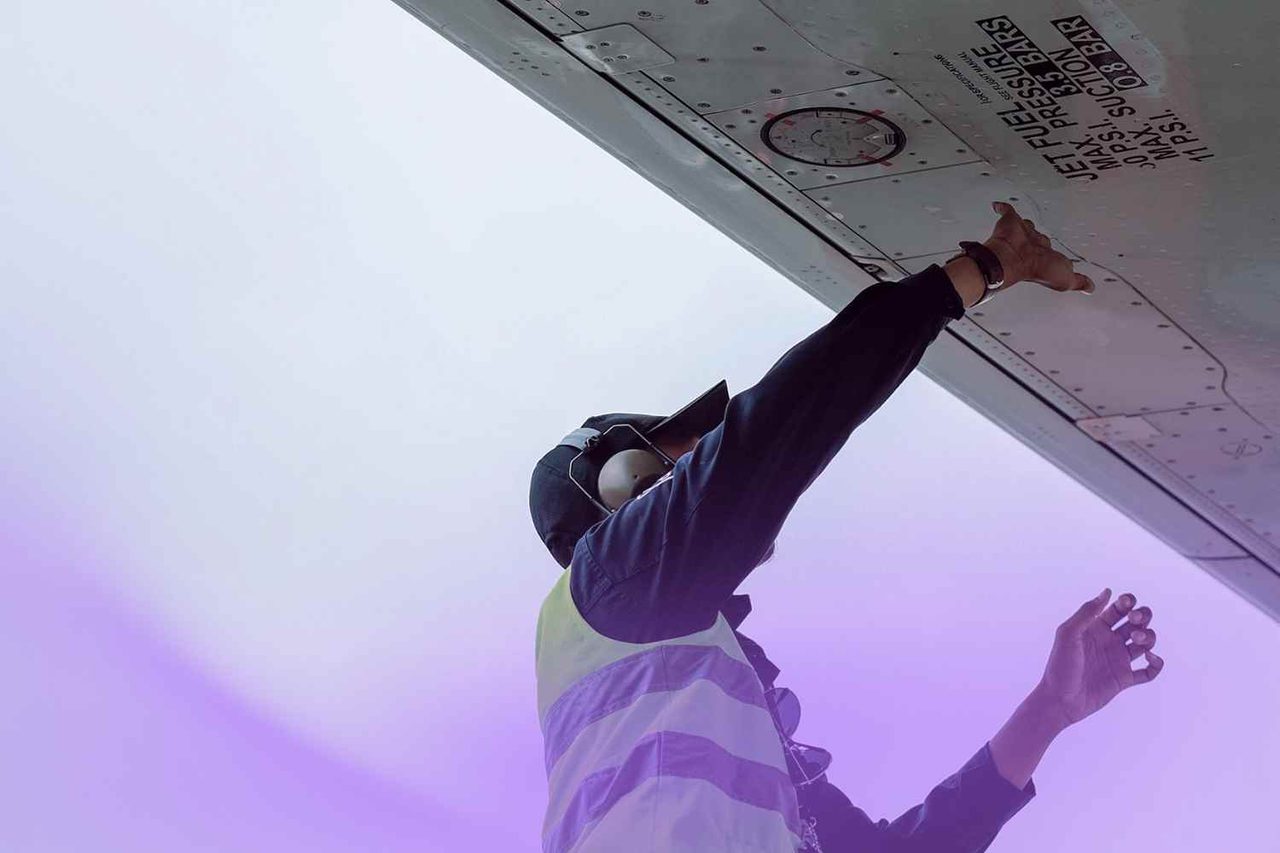 Man working on airplane wing is safety vest
