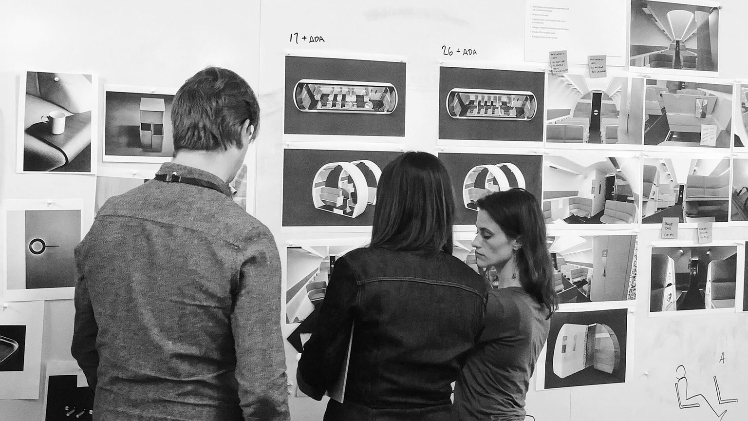 Three people standing at whiteboard review design concepts