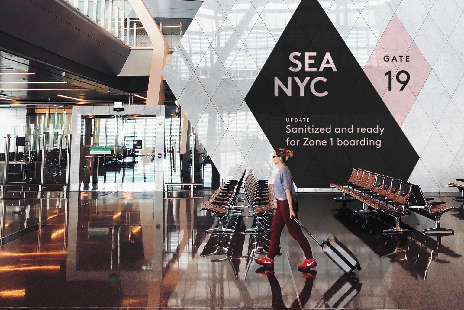Women walking through airport with red shoes and rolling bag in front of digital display