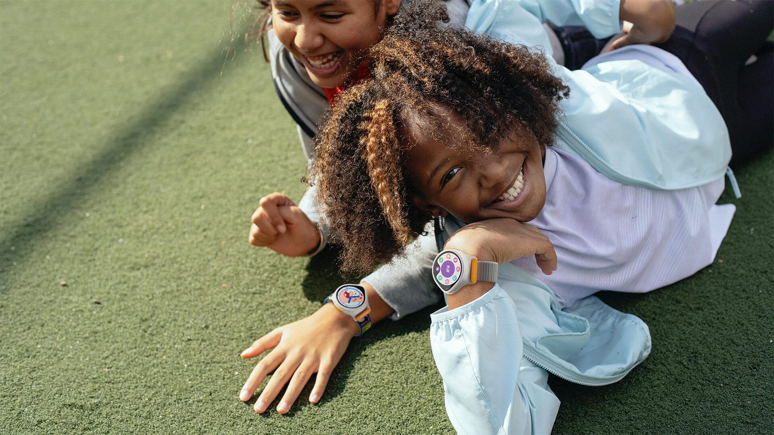 Two kids laying on the grass with NickWatches on